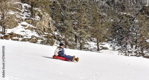 Pretty young girl sledding in a beautiful scenery of the snowy mountains