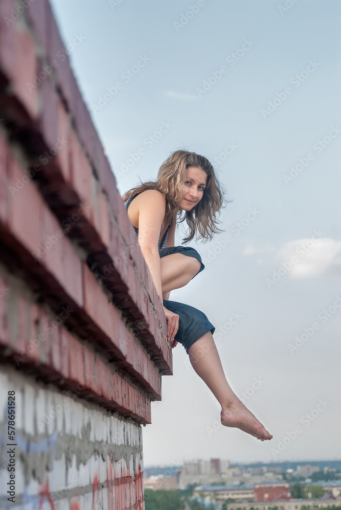 Young attractive woman relaxes on edge of high building roof