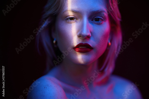 Beauty portrait of a blond woman looking at the camera. Photo taken with photo gels. Neon colors. Viva magenta, color of the year.