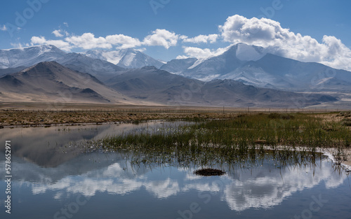 Scenic high altitude mountain landscape with blue sky and clouds reflection in water near Karakul lake on Pamir Highway  Murghab  Gorno-Badakshan  Tajikistan