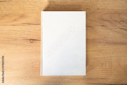 white book with an empty pesto for text and design on a wooden background