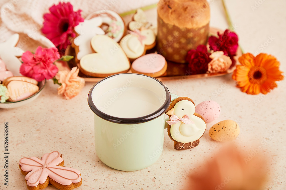 Mug with milk and Easter cake, decorated cookies among flowers. Spring cozy aesthetic background. Mug with milk and Easter cake, decorated cookies among flowers. Spring cozy aesthetic background.