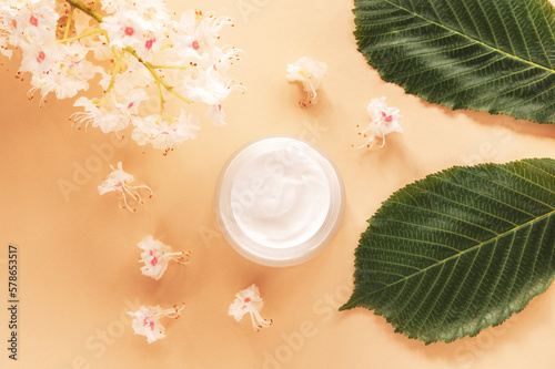 Cream jar and Horse chestnut leaf and flowers. Natural organic cosmetics concept. Top view, flat lay photo