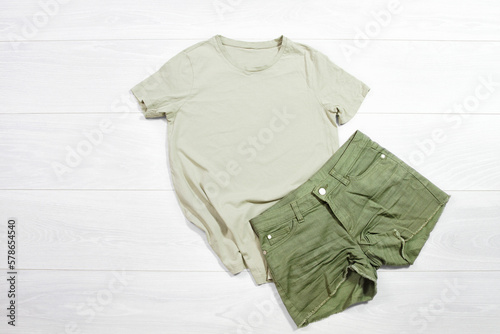 Khaki female t shirt mockup flat lay on wooden background. Summer clothing canas. Mint trousers. Top front view t-shirt. Template blank copy space. Summertime season photo