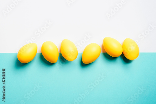 Yellow Easter eggs on white and blue background. Top view, flat lay, copy space