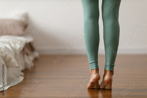 Young woman in sports leggings walks barefoot on the warm floor in the  bedroom. Stock Photo by atercorv