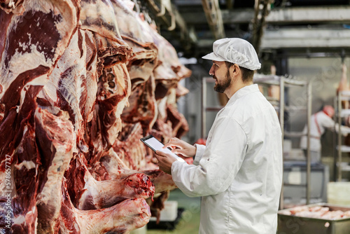 A slaughter house supervisor is assessing quality of fresh meat. photo