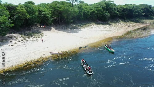 An aerial view of rural people from the Luvale tribe crossing over the Zambezi River by paddle canoe from the west bank to Chavuma village in Zambia.