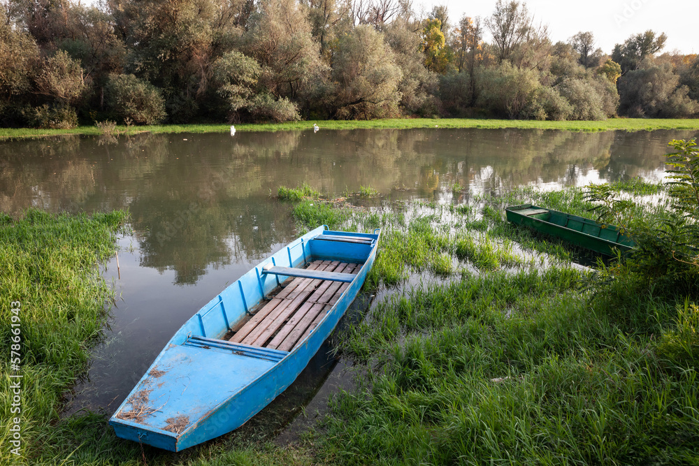 Panorama of an abandoned rowing boat, an blue small boat, resting in the neglected shore of the tamis timis river in Jabuka, in Vojvodina, Serbia, in central Europe