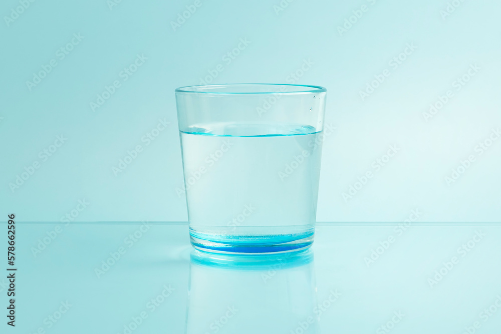 Glass with pure clear melt water on blue background Glass with pure clear melt water on blue background