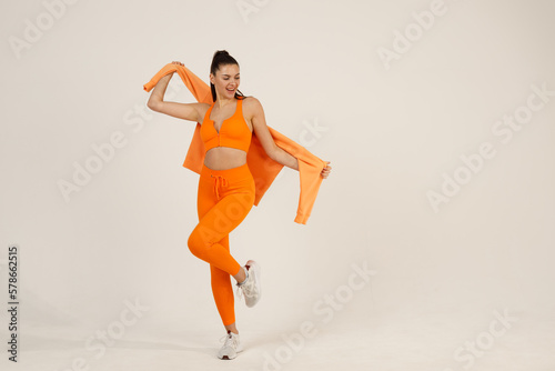 Young positive smiling woman in orange fitness sport outfit cloth studio isolated shot.