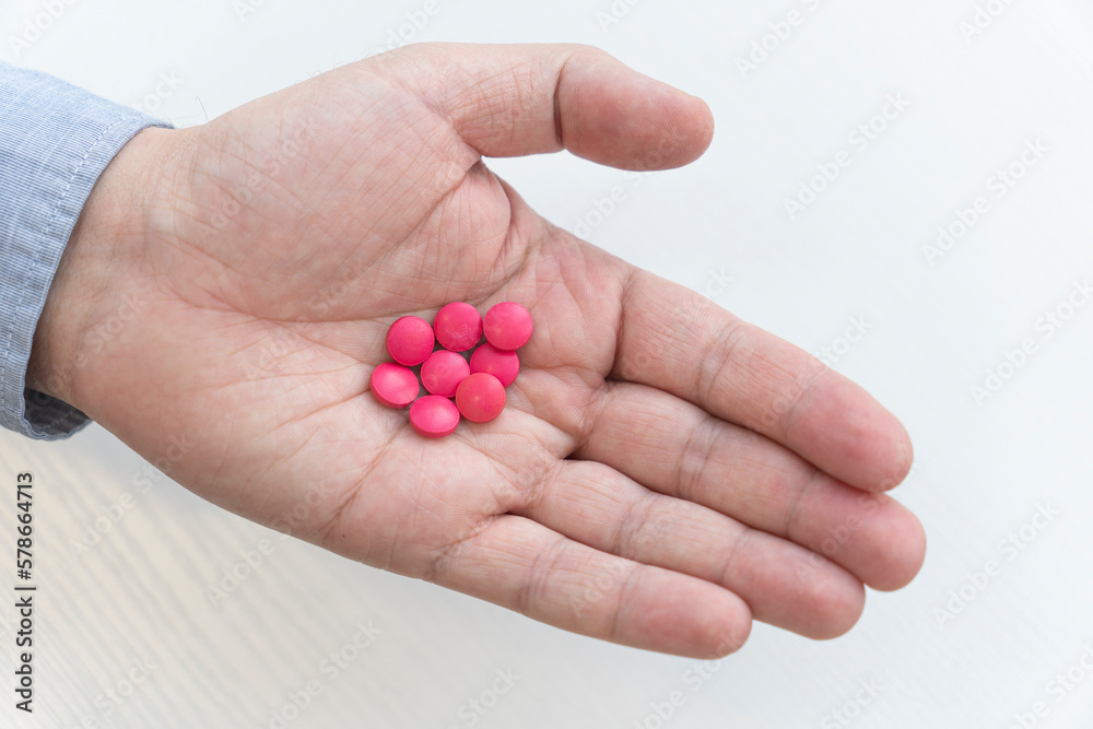 red pills in a man hand close-up. the concept of treatment. antiviral agent. top view red pills in a man hand close-up. the concept of treatment. antiviral agent. top view