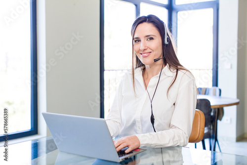 young pretty woman smiling happily with a hand on hip and confident. telemarketer concept