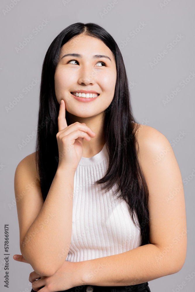 Inquisitive curious asian young adorable girl thinking having an idea looking up on grey background copyspace. Inquisitive curious asian young adorable girl thinking having an idea looking up on grey background copyspace.