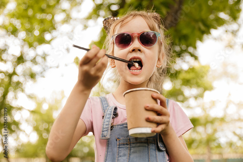 little girl drinking cocoa in the summer in the park