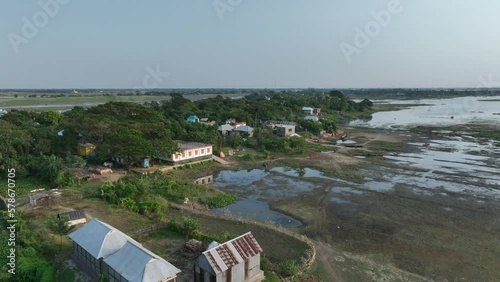 Drone camera moves over the small village and rice fields after harvesting in Bhasania Dari Char (river island village), Bangladesh. photo