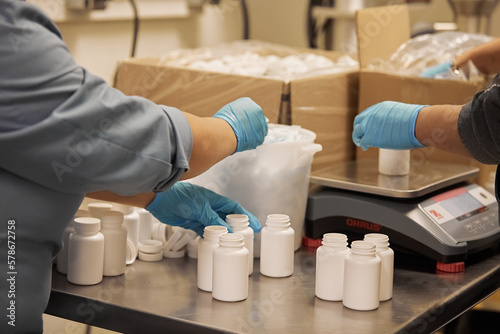 Dietary supplements packaging by hand in HDPE bottles wearing gloves