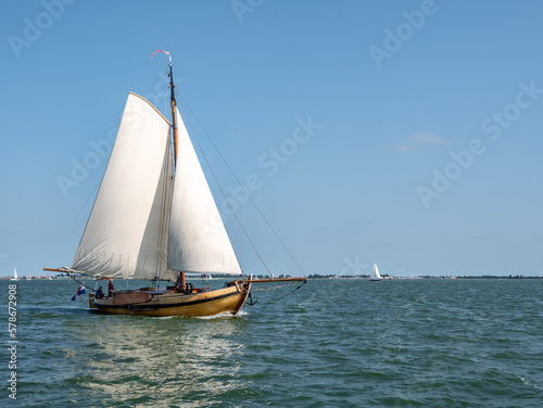 Traditional classic sailboat sailing under full sails on IJsselmeer lake, Netherlands
