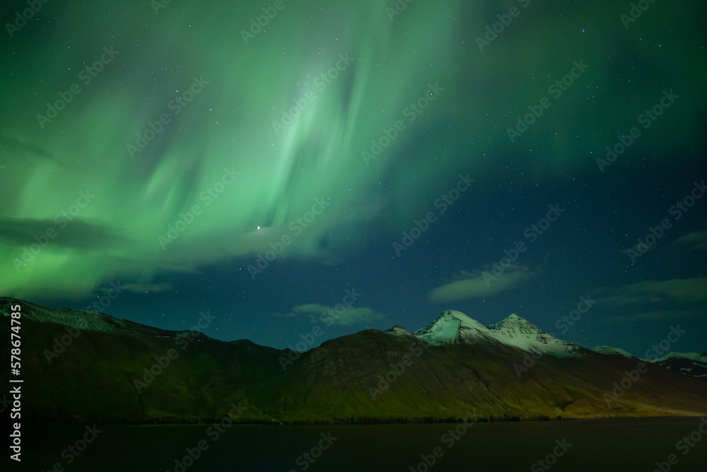 Aurora borealis over snowy peaks in mountain fjord, Iceland Aurora borealis over snowy peaks in mountain fjord, Iceland