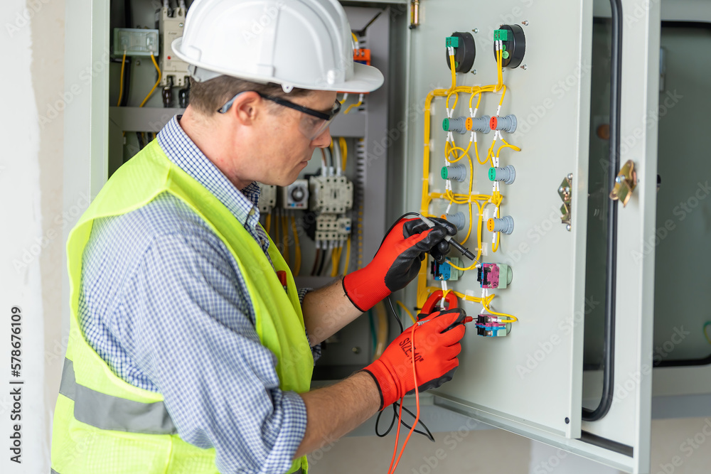 Electrician installing electrical wires and multimeter fuse switch box in hands of electrician detail Electrician installing electrical wires and multimeter fuse switch box in hands of electrician detail
