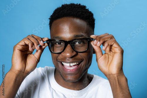 Delighted handsome attractive pretty young student guy in glasses clever smart student pupil over blue background in studio isolated.