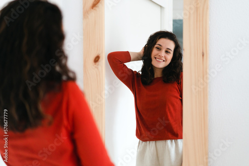 Young beautiful woman with a new sweater looking in the mirror