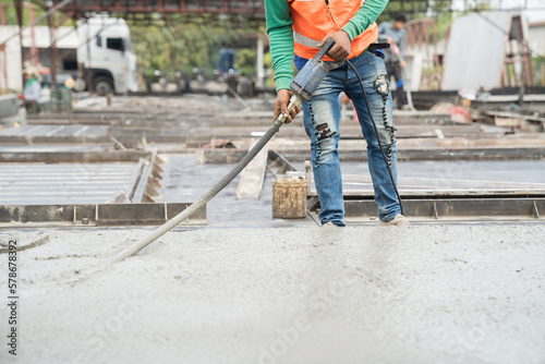 Construction technician uses concrete vibration generator during leveling concrete floor. Construction worker using concrete vibrator removal air bubbles for maximum strength in concrete photo