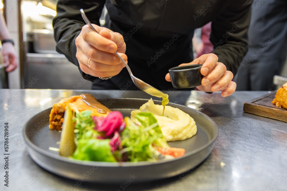 chef hand preparing Meat Pie with mashed potato and salad on restaurant kitchen