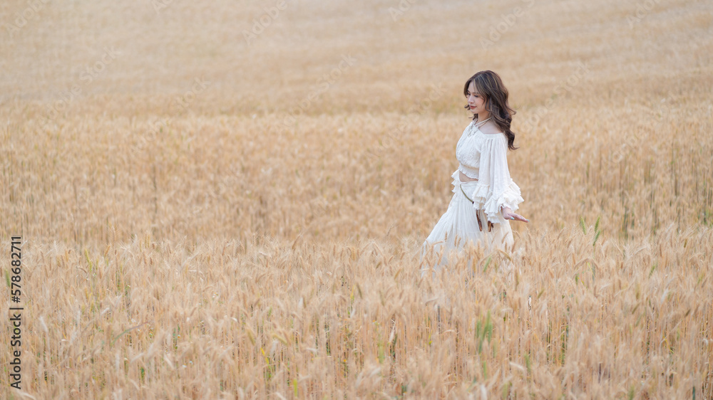 Beautiful Asian women were in white dresses relaxed and happy in the Barley rice field season golden color of the wheat plant. Freedom traveler, dreamy portrait in a wheat field. Beautiful Asian women were in white dresses relaxed and happy in the Barley rice field season golden color of the wheat plant. Freedom traveler, dreamy portrait in a wheat field.