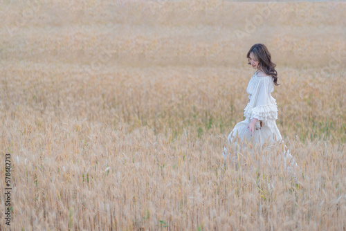Beautiful Asian women were in white dresses relaxed and happy in the Barley rice field season golden color of the wheat plant. Freedom traveler  dreamy portrait in a wheat field.