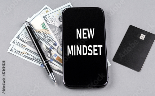 Credit card and text NEW MINDSET on smartphone with dollars and pen. Business concept