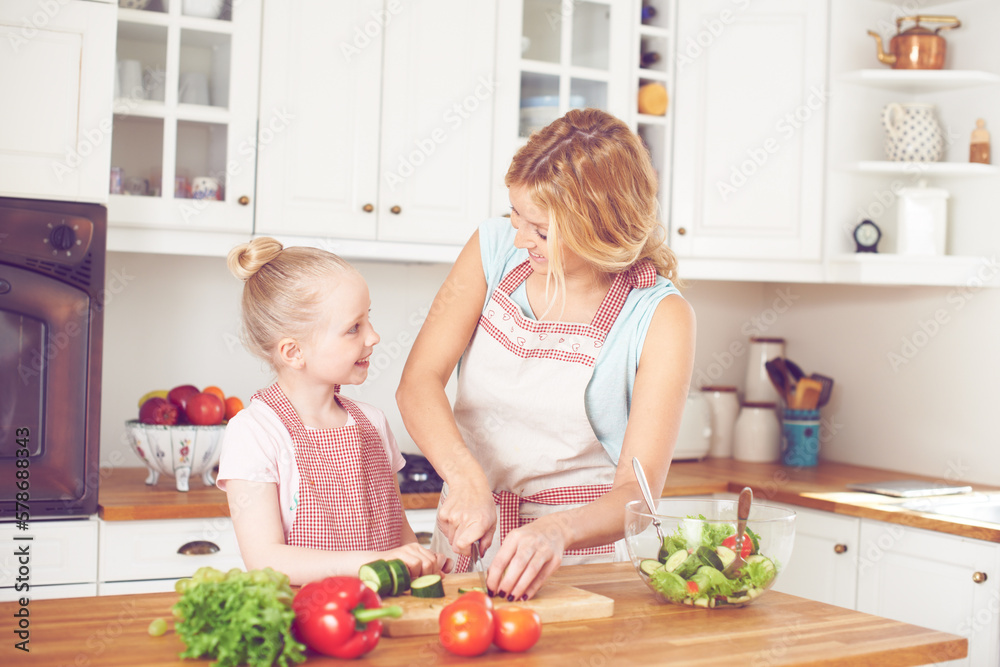Teaching her how to make a salad. Young mother and her daughter making a salad together.