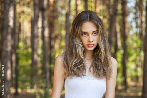 Portrait of a young beautiful woman posing in the forest © Andrey_Arkusha