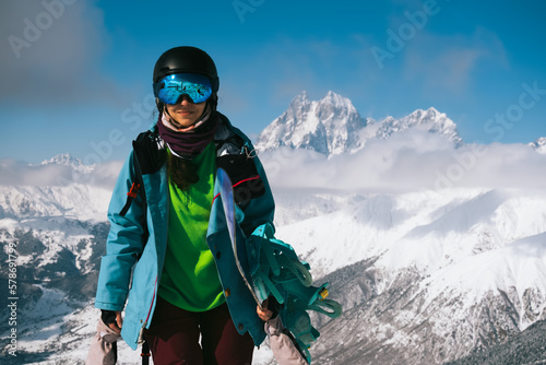 Snowboarder woman standing with snowboard beautiful mountain peaks covered with snow on background