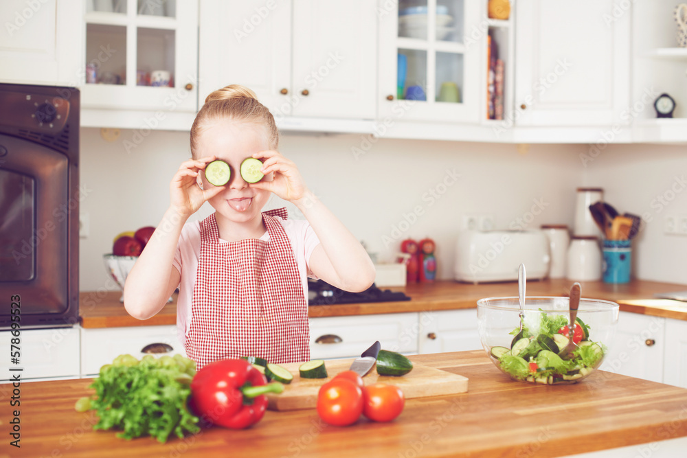 Kitchen fun. Cute little girl playfully holding cucumber slices over her eyes. Kitchen fun. Cute little girl playfully holding cucumber slices over her eyes.