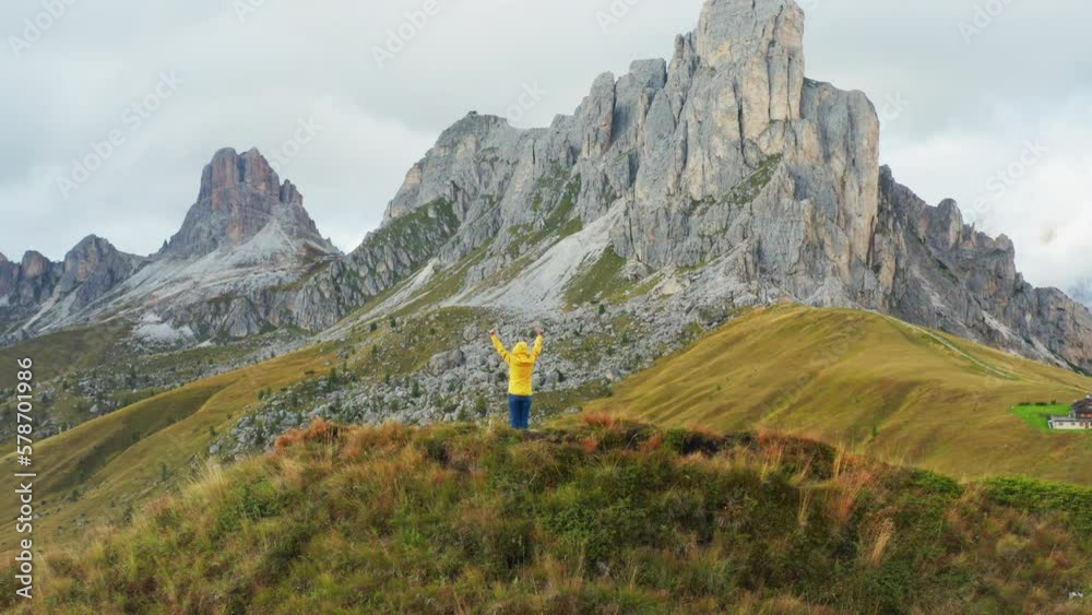 Hiker reaching hands to sky enjoys exploring mountain nature on Pass Giau. Female tourist looks around and enjoys vacation on high mountain range Hiker reaching hands to sky enjoys exploring mountain nature on Pass Giau. Female tourist looks around and enjoys vacation on high mountain range