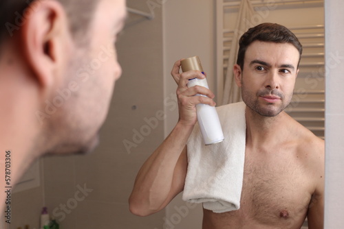 Man using hair spray in the bathroom