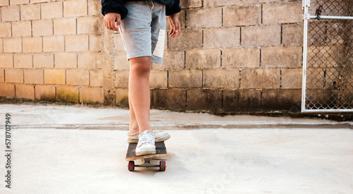 Close-up of a boy practicing standing on a skateboard with his dog.