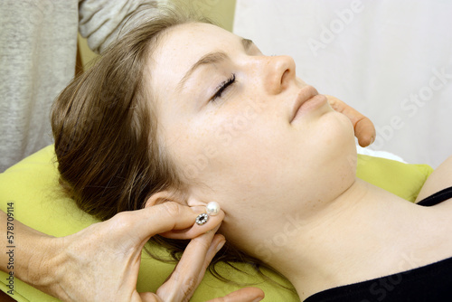 Osteopath and physiotherapist treating patient's head and ears photo