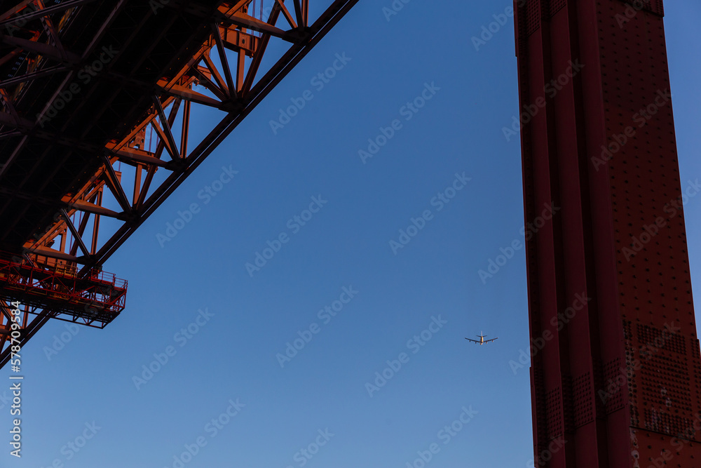View of side red bridge and airplane fly on the blue sky