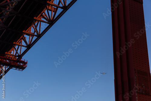 View of side red bridge and airplane fly on the blue sky