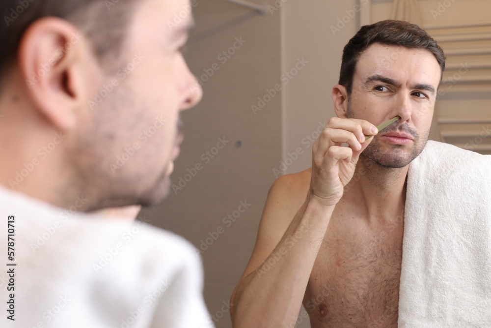 Fototapeta premium Man using tweezers to pluck nose hairs