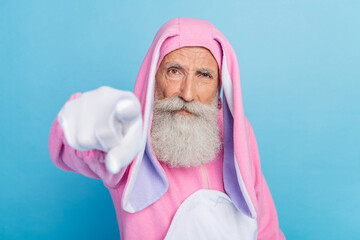 Photo of angry serious pensioner guy dressed bunny kigurumi pointing finger you isolated blue color background
