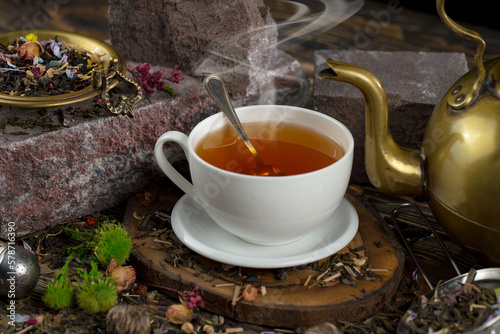 Sweet, hot tea with dry tea leaves, on an old background.