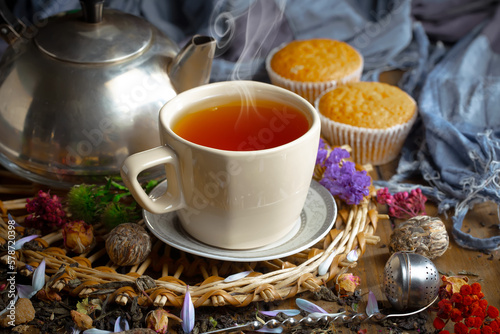 Sweet, hot tea with dry tea leaves, on an old background.