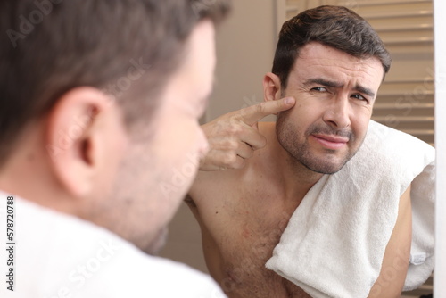 Man observing his wrinkles in the mirror 