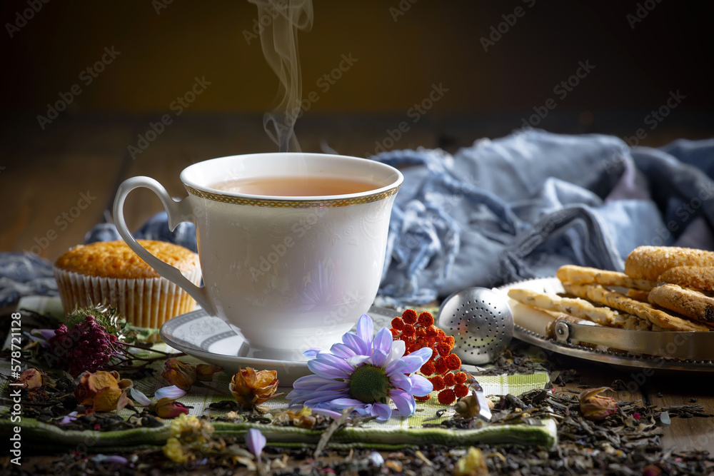 Fototapeta premium Sweet, hot tea with dry tea leaves, on an old background.