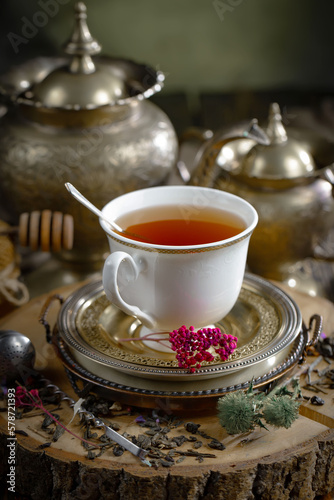 Sweet, hot tea with dry tea leaves, on an old background. © Karnav