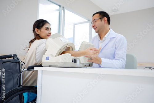 Male doctor measuring blood pressure of female patient at hospital.