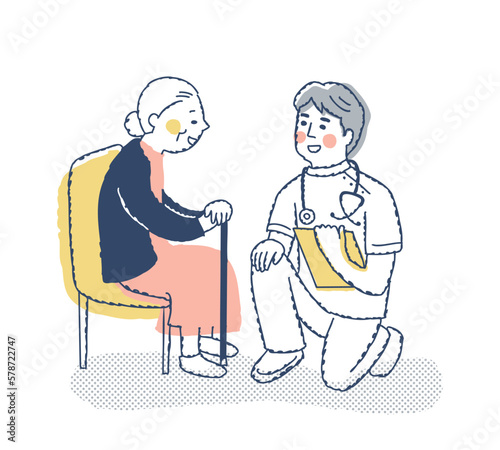 シニア女性としゃがんで話す医療従事者